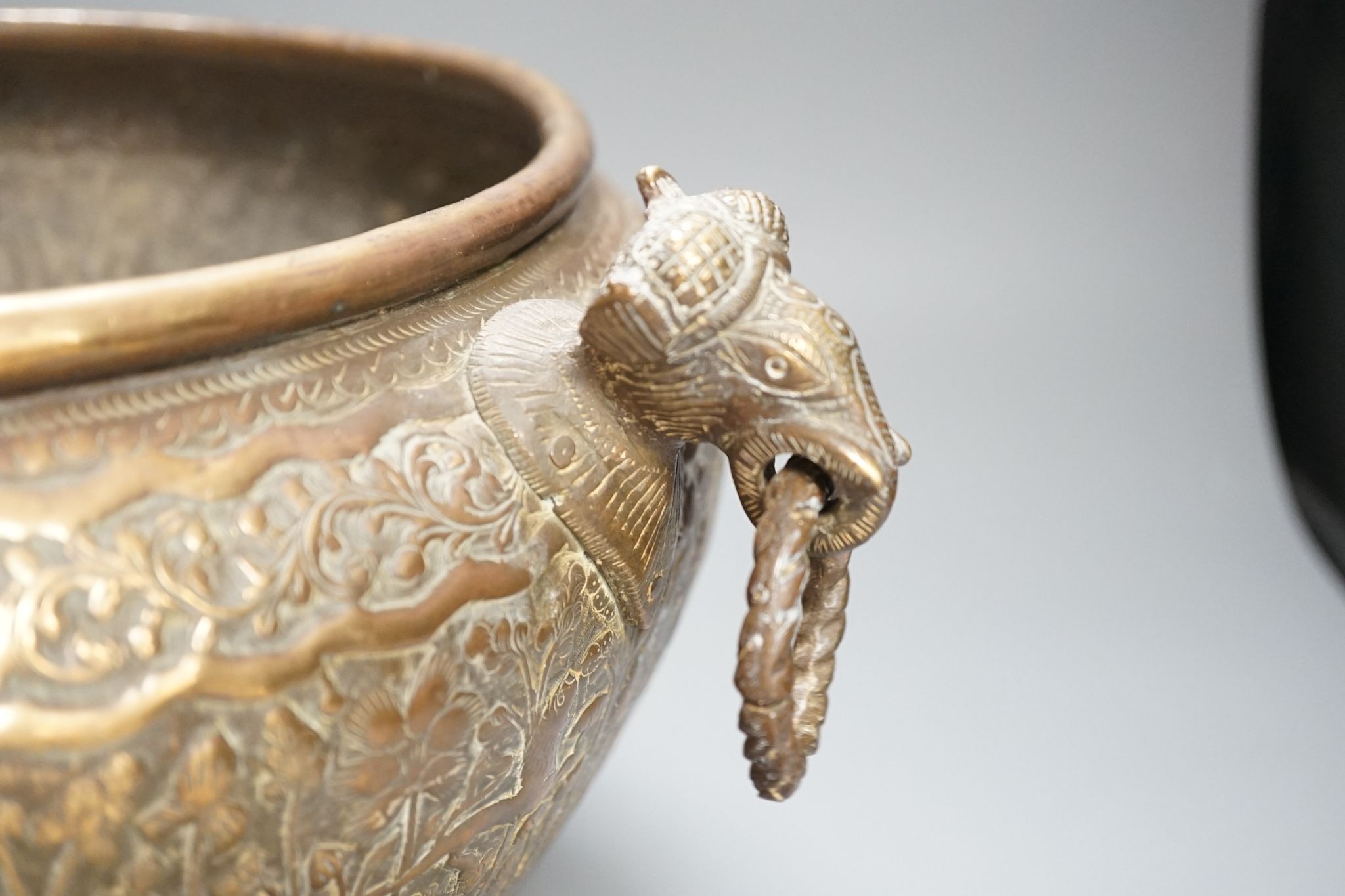 19th century hand engraved British Indian brass jardinière planter vase, finely engraved depicting scenes in an Indian forest with game hunting and elephants; with elephant head handles; original patina.
